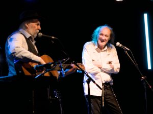 John Otway looking amused with Wild Willy Barrett playing guitar