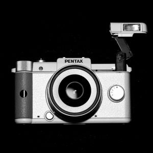 A Pentax Q camera with 01 Standard Prime Lens shown with flash extended